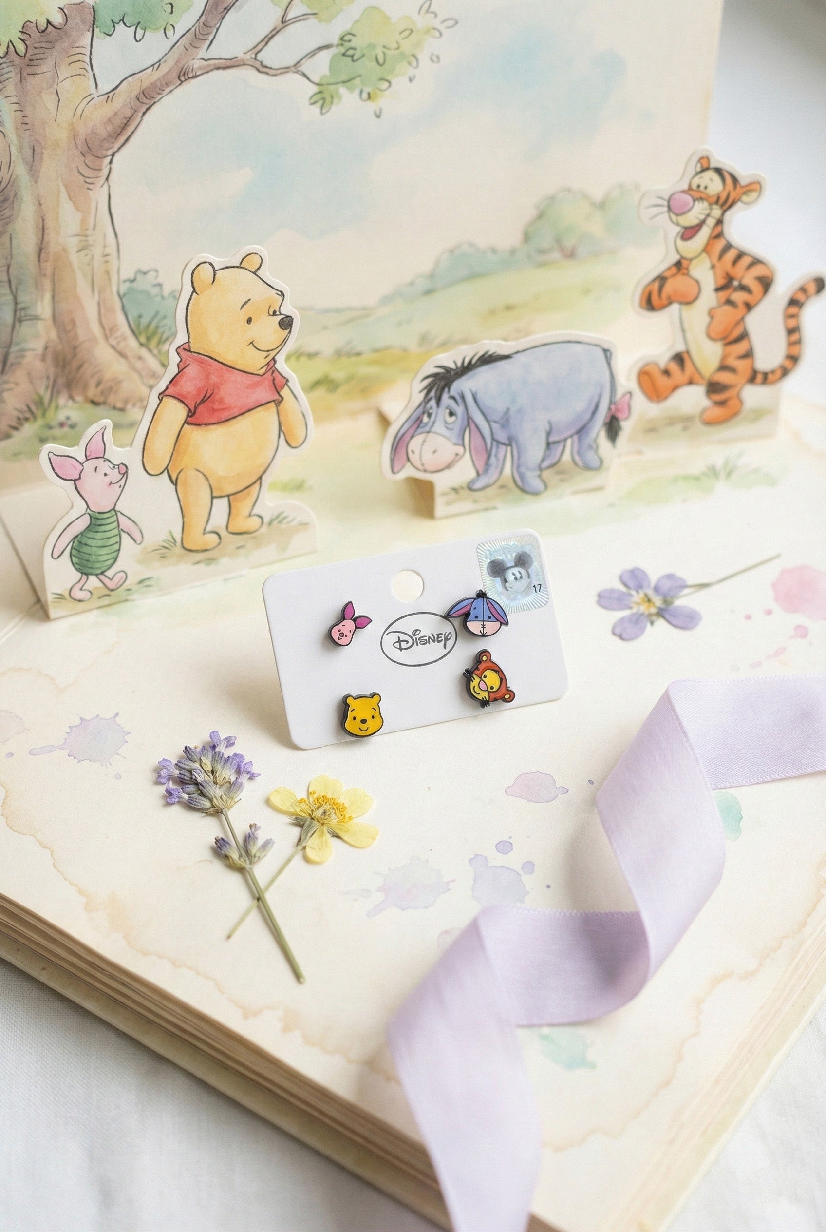 Four-piece Winnie the Pooh character stud earrings displayed on Disney illustrated book page