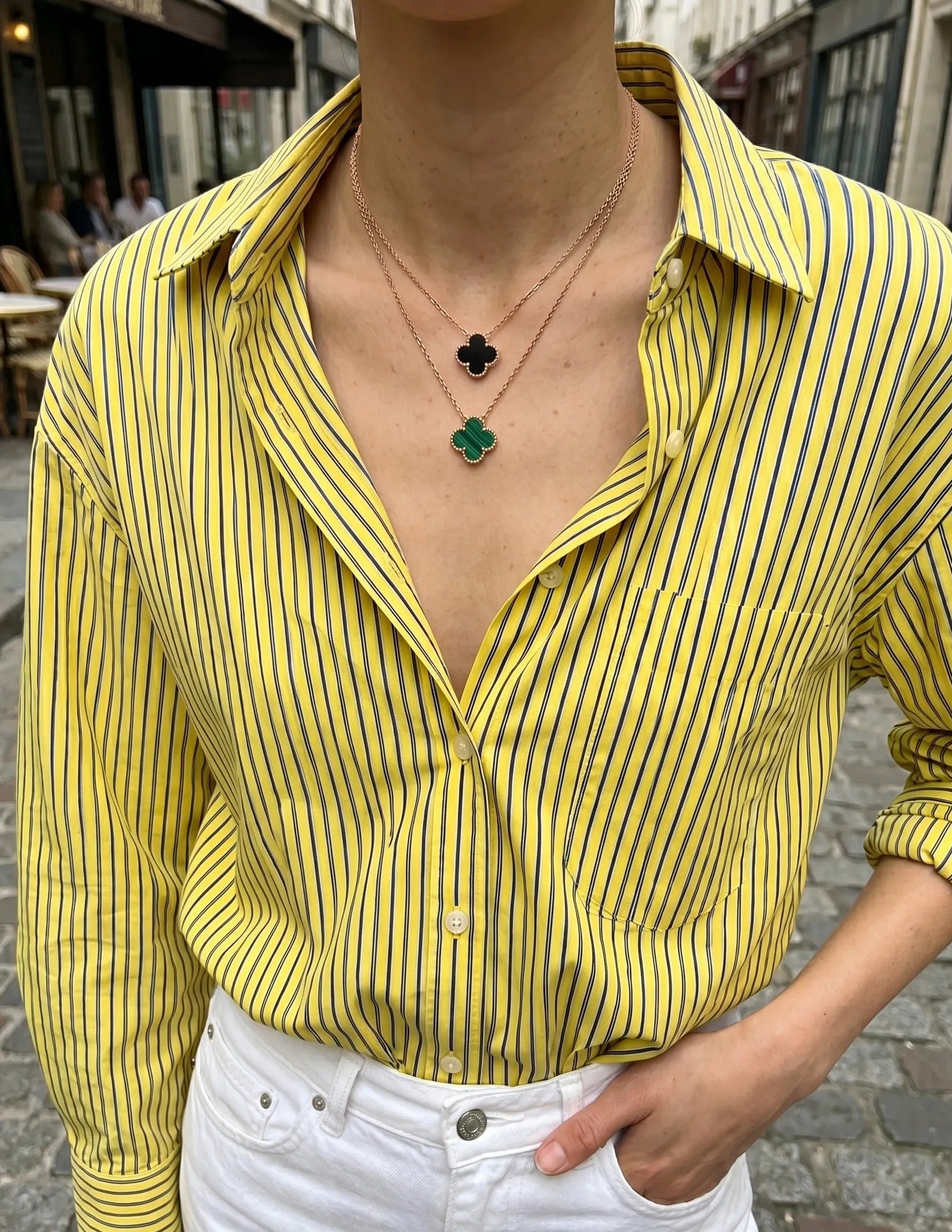 Layered clover necklace stack onyx black malachite green on yellow stripe button-down shirt K-style necklace layering inspo.