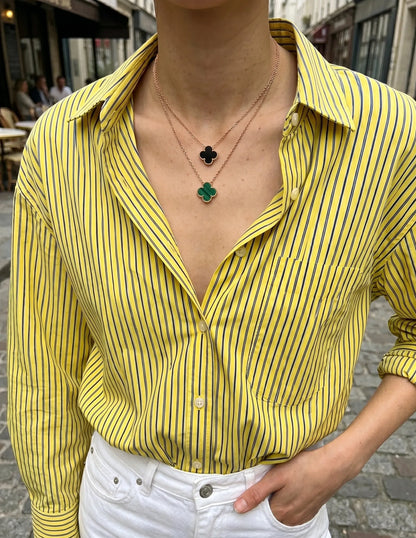 Layered clover necklace stack onyx black malachite green on yellow stripe button-down shirt K-style necklace layering inspo.
