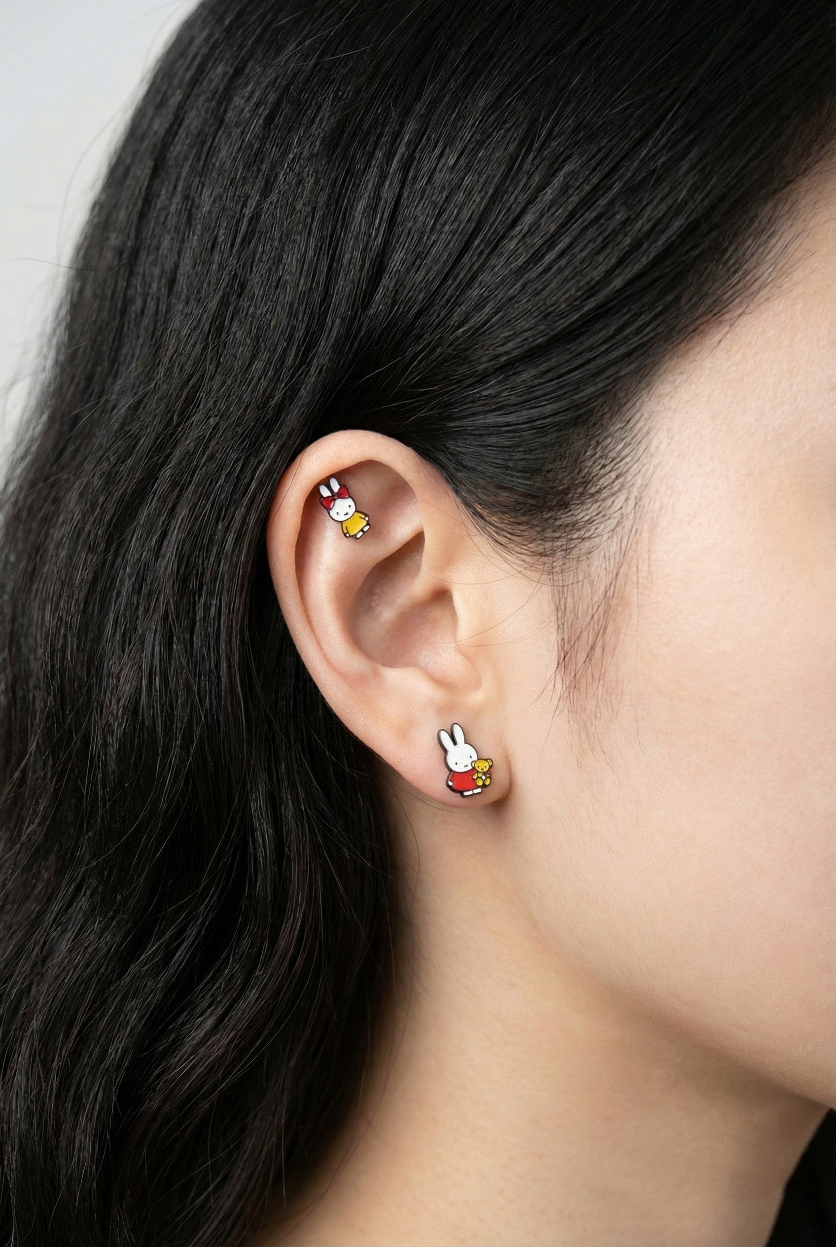 Miffy rabbit piercing worn on inner conch cartilage with yellow dress and red bow