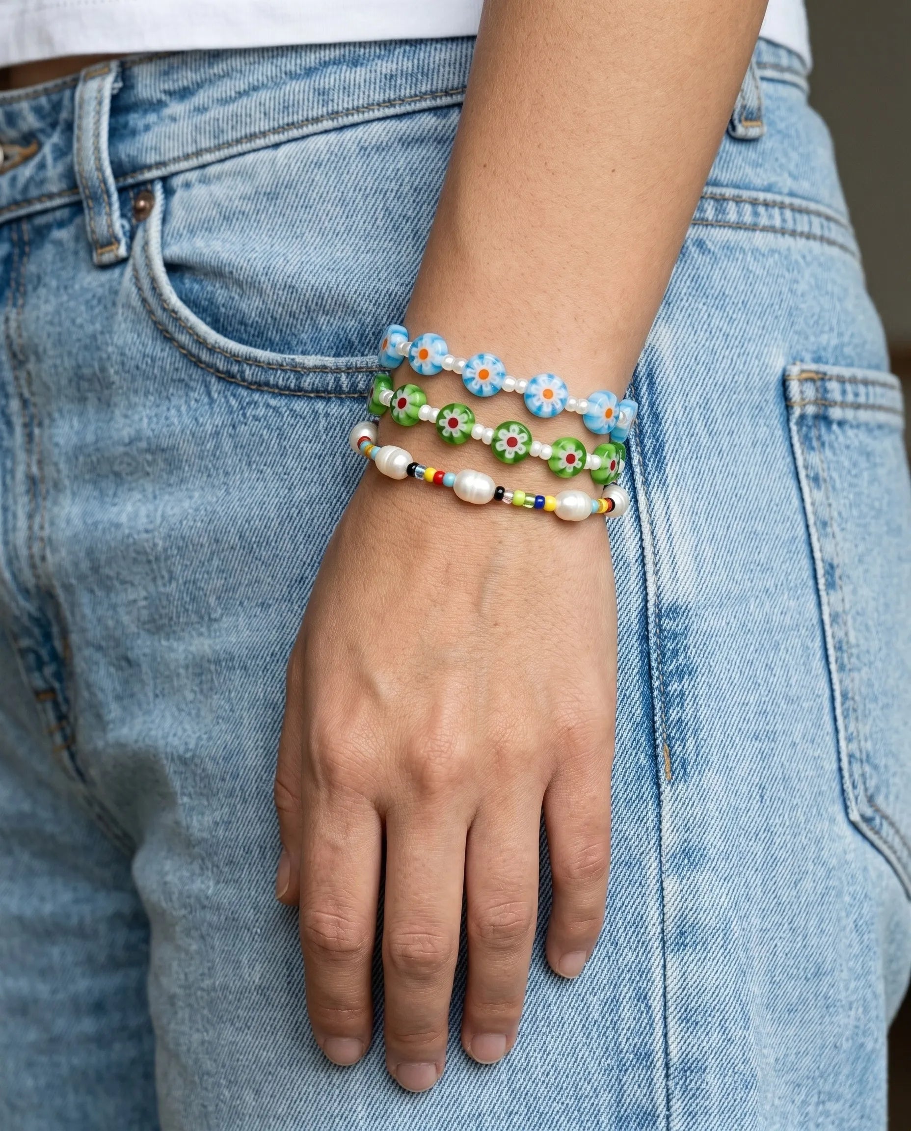 K-style summer bracelet stack — blue and green glass flower bead bracelets layered with colorful seed bead pearl bracelet, denim casual look.