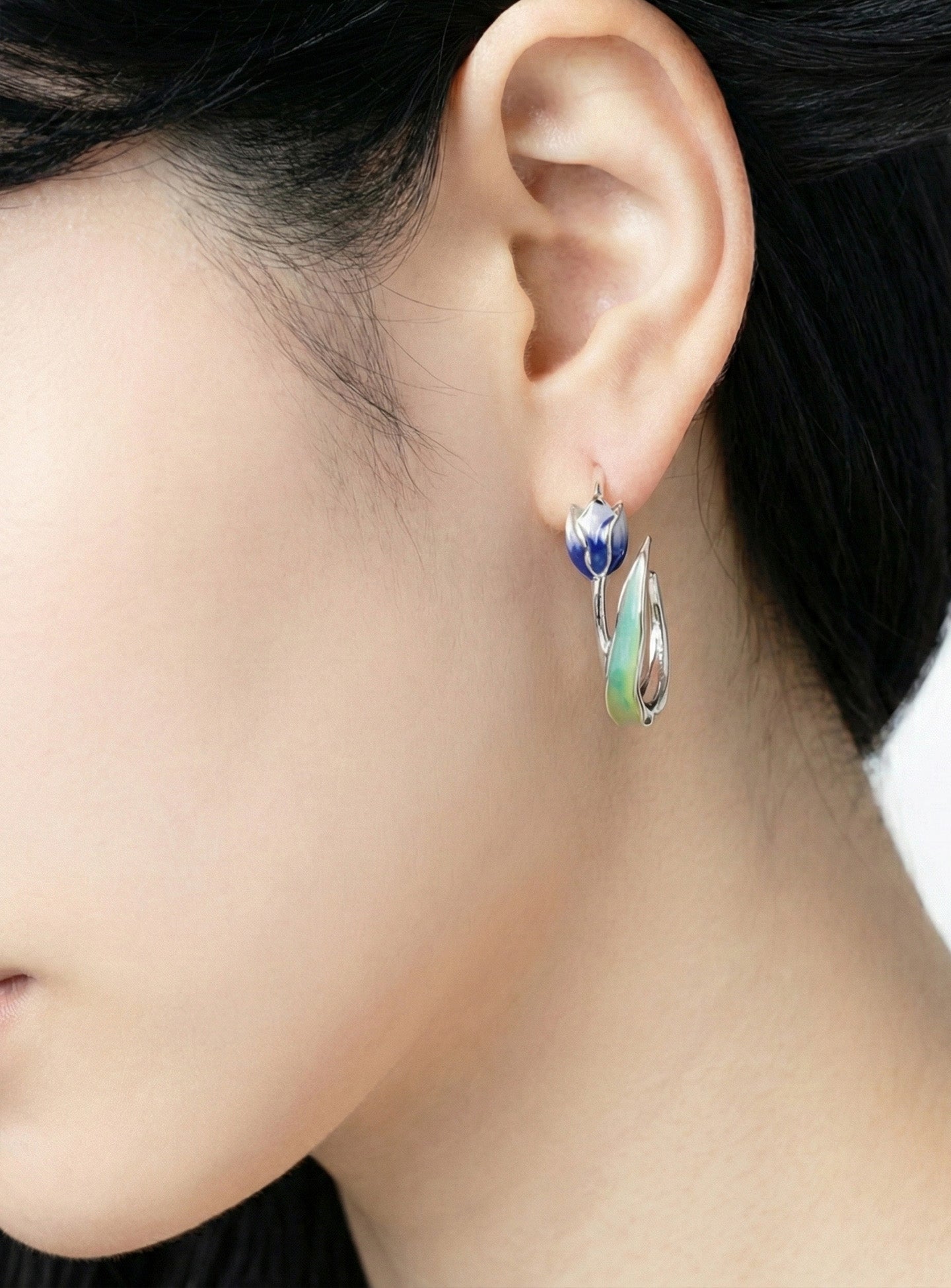 Close-up of blue watercolor tulip flower hoop earring on ear