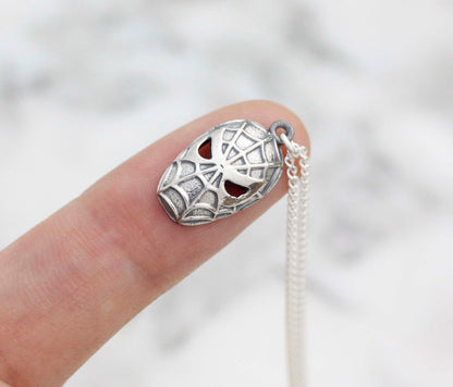 Hand holding a small 1x2cm unique silver spider pendant showing handmade texture