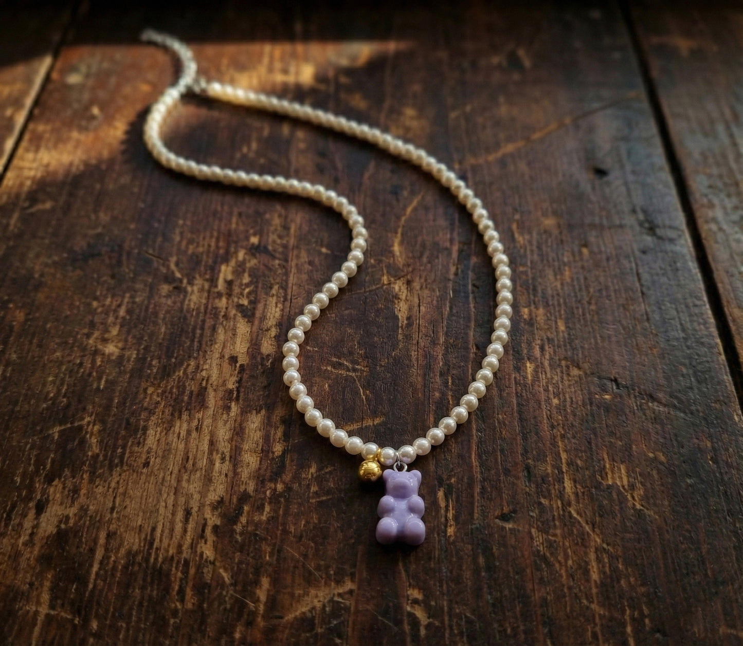  Lavender pearl beaded necklace with gummy bear pendant on rustic wooden background