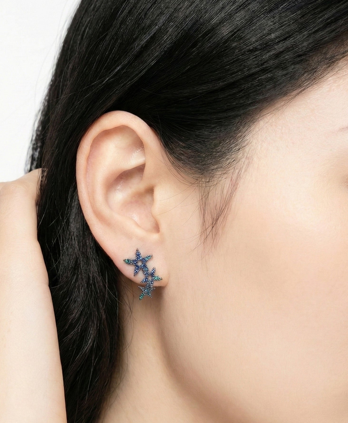Triple star cluster stud earring in micro-pavé blue cubic zirconia on earlobe