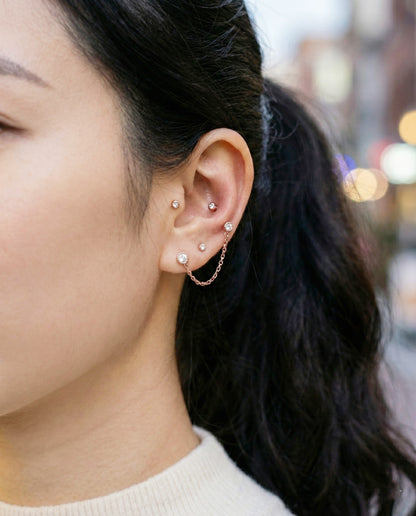 Rose gold chain connector piercing with multiple ear piercings
