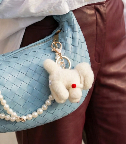 Close-up of Bichon keychain on bag zipper with gold-tone hardware