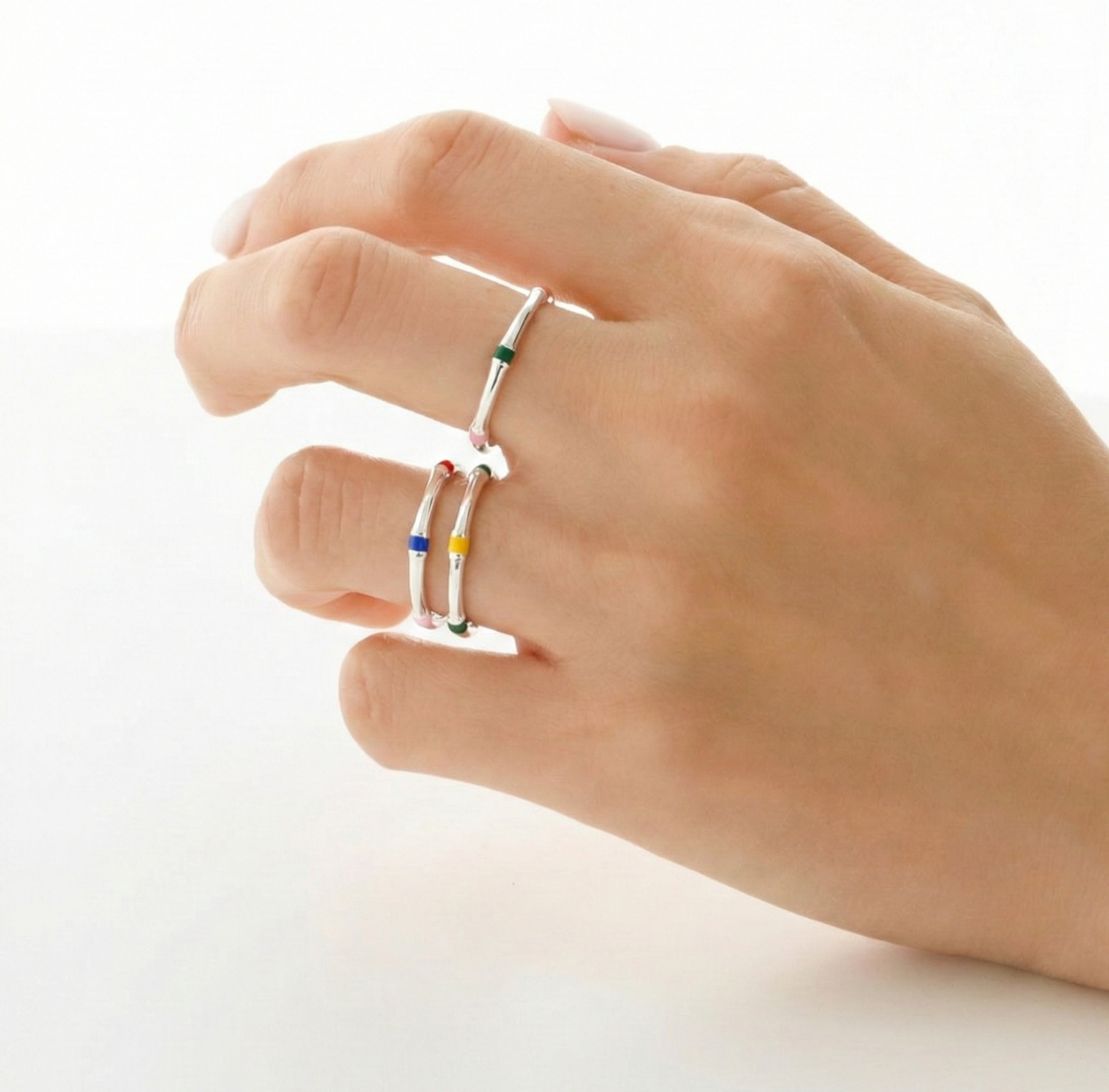 Model wearing 925 sterling silver colorful enamel open rings stacked on multiple fingers, white background, dainty stackable ring styling