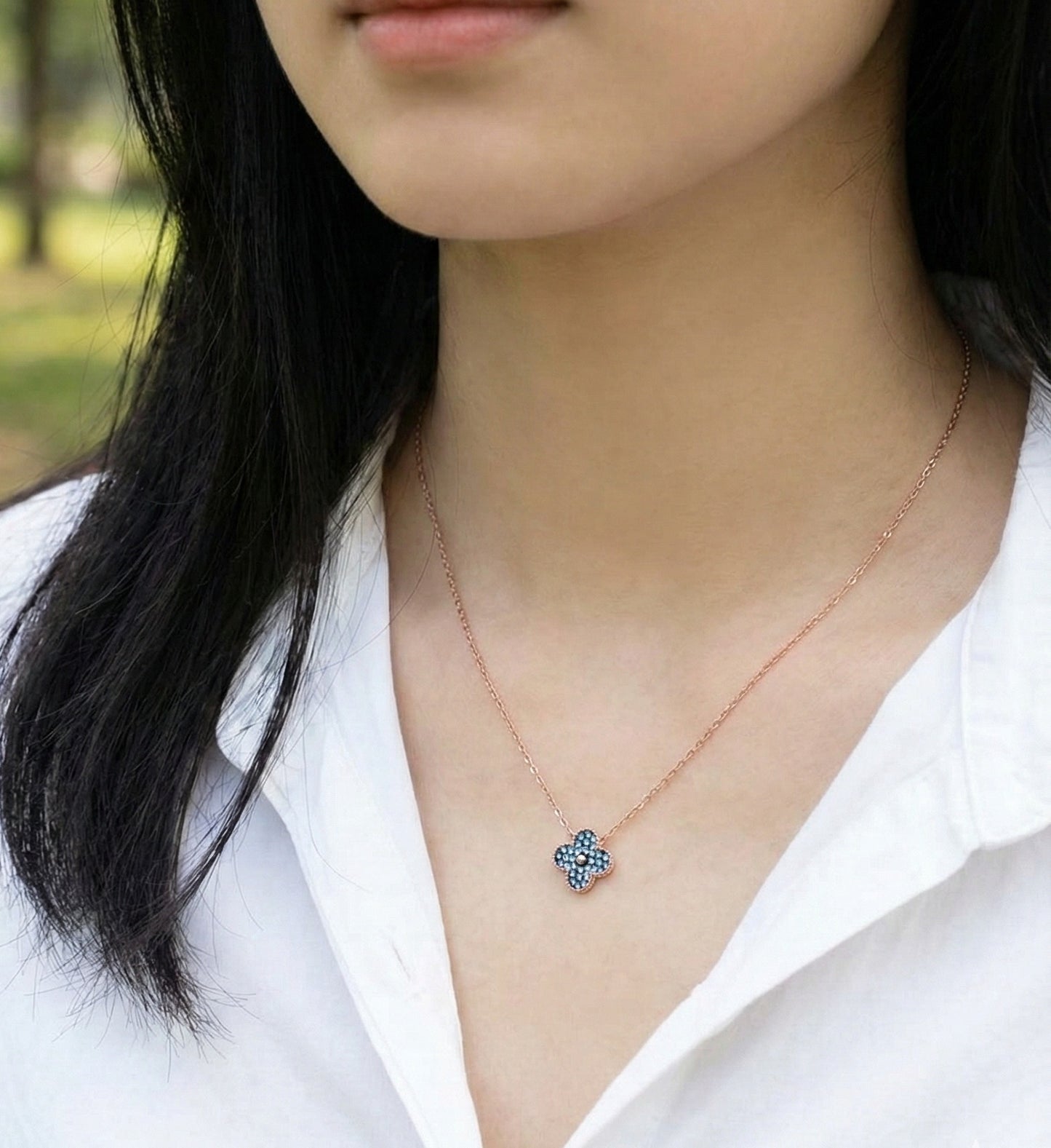Blue clover pendant necklace on woman's neck, minimalist jewelry styling