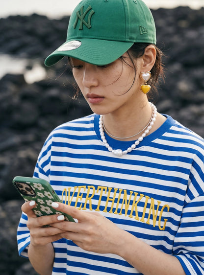 Yellow heart drop earrings paired with green ballcap and striped tee, K-style statement jewelry inspo.