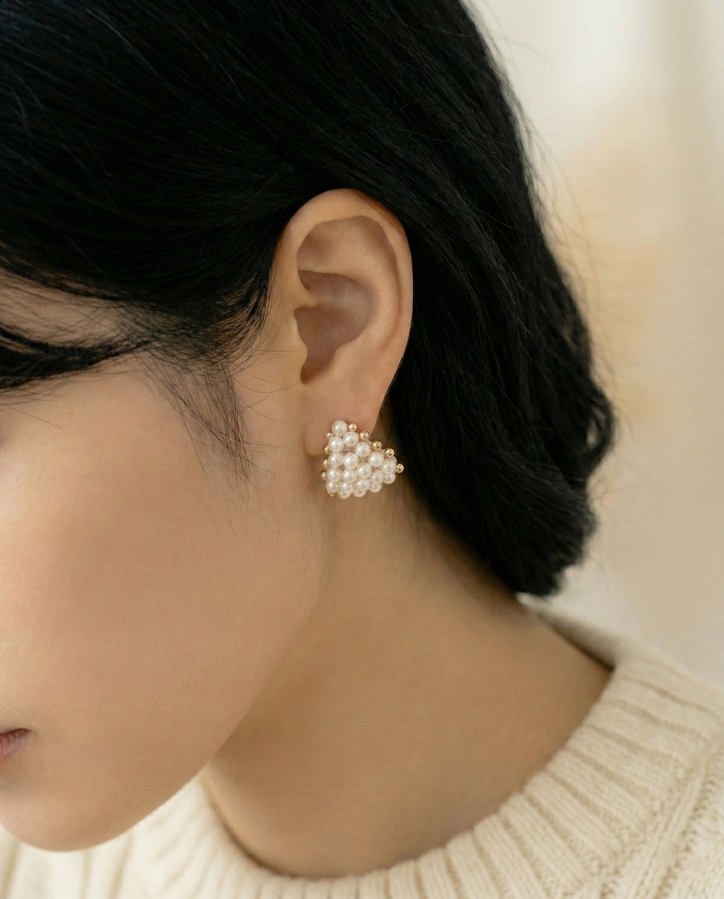 Woman wearing gold pearl heart earrings with cream turtleneck sweater - front angle