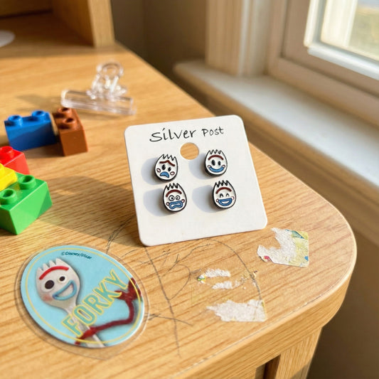 Forky face stud earrings set with 4 expressions on white card next to colorful building blocks and Forky badge