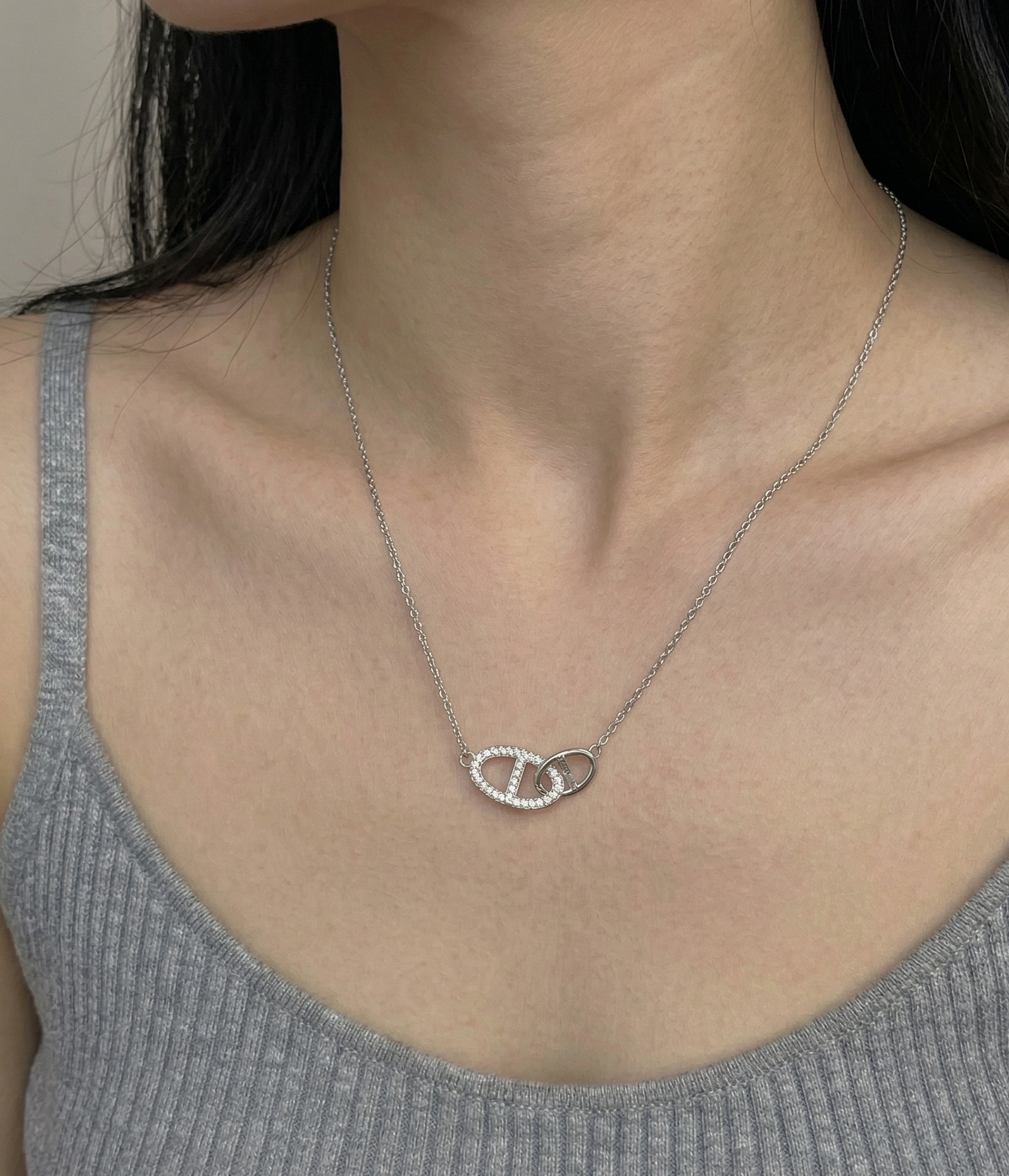 Model wearing dainty 925 sterling silver pavé double ring necklace with a gray sleeveless ribbed top, showing collarbone drape