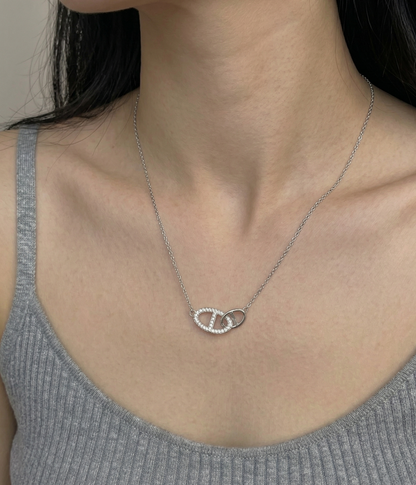 Model wearing dainty 925 sterling silver pavé double ring necklace with a gray sleeveless ribbed top, showing collarbone drape