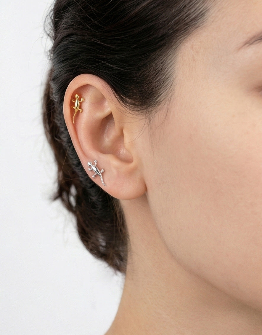 Gold and silver gecko piercings worn together on helix and lobe, animal stud earrings layered styling