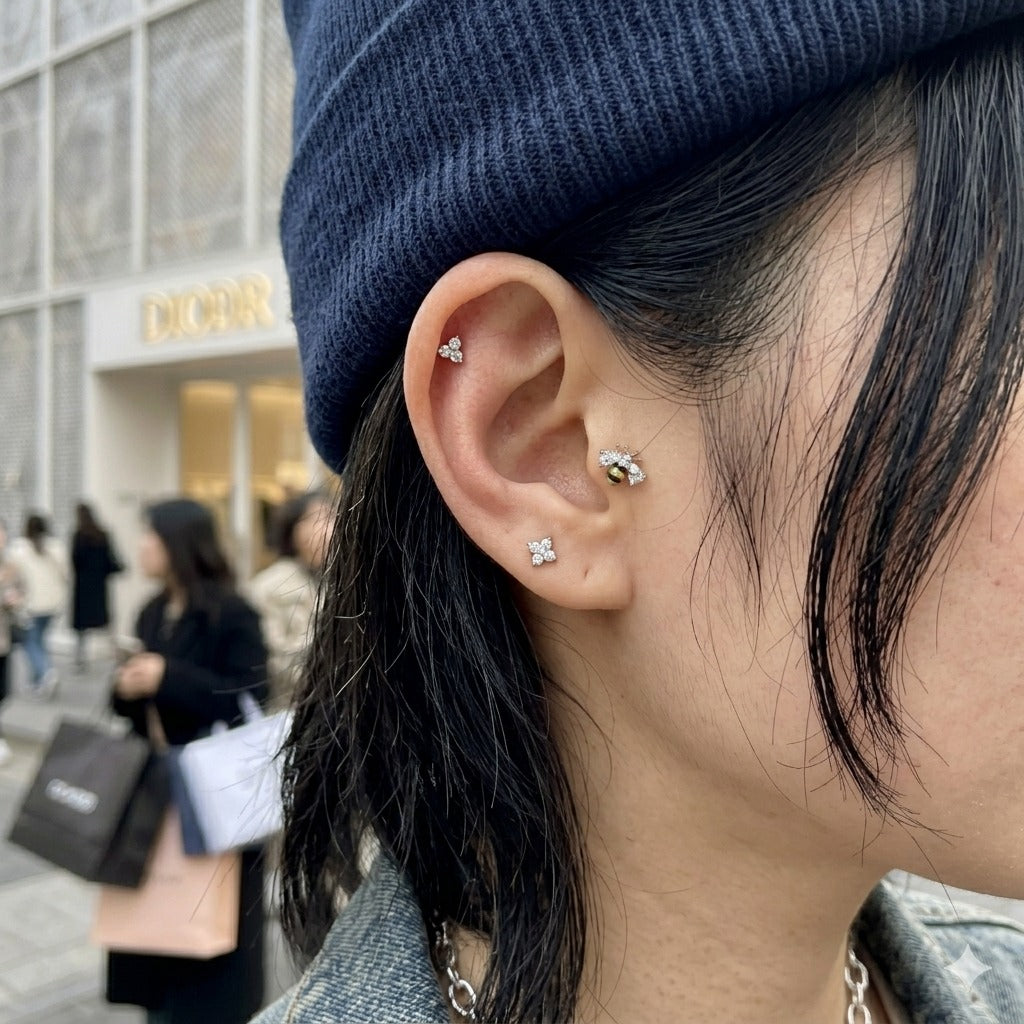 Seoul street aesthetic ear stack inspo with bumblebee CZ inner conch piercing, layered with flower cluster lobe stud, clean girl vibe.