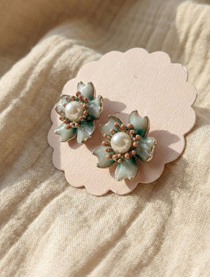  Detail shot of vintage bloom pearl stud earrings showing translucent petal tips and antique bead work on beige linen