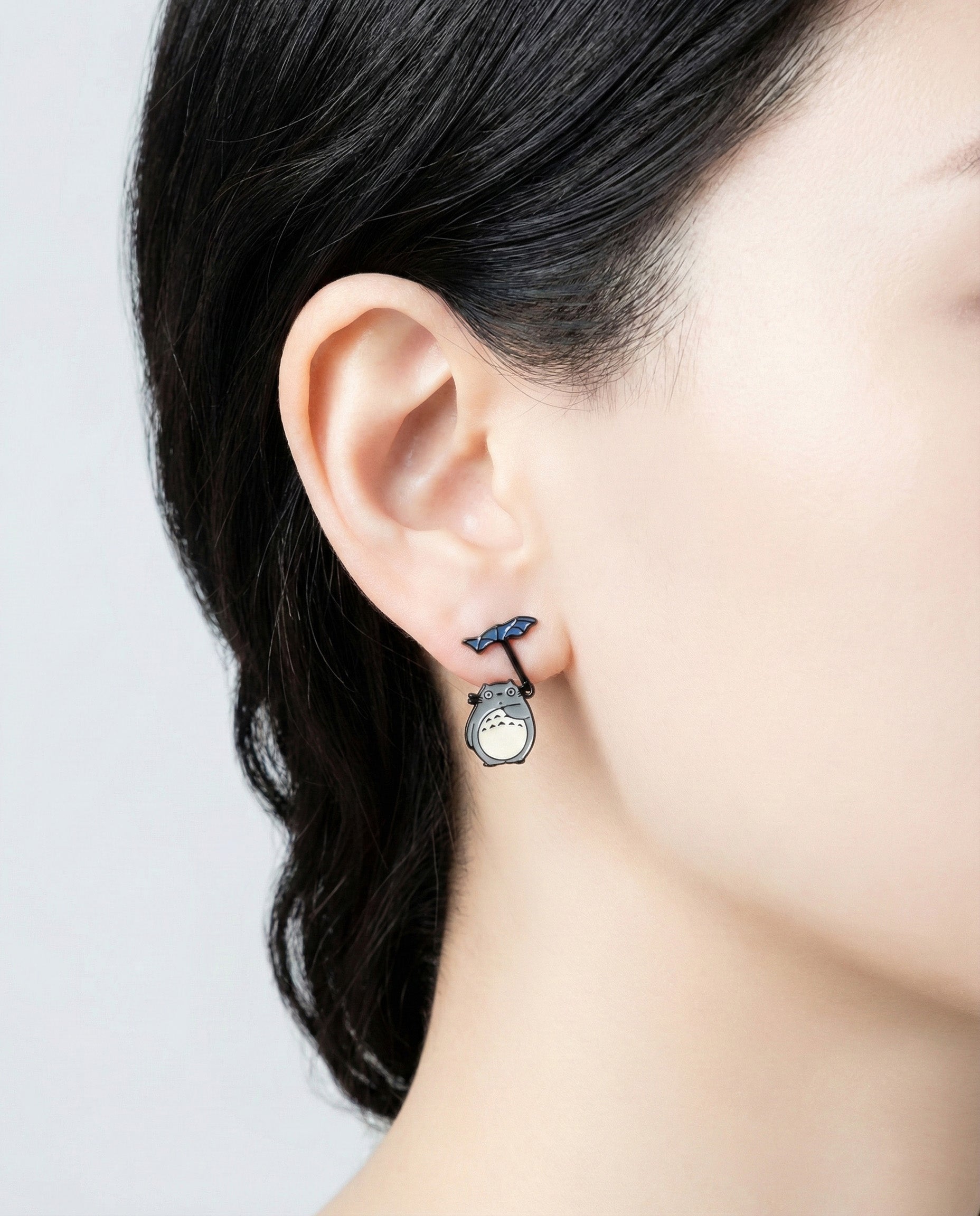 Close-up of handmade Totoro earring with blue umbrella charm, mismatched Ghibli earrings