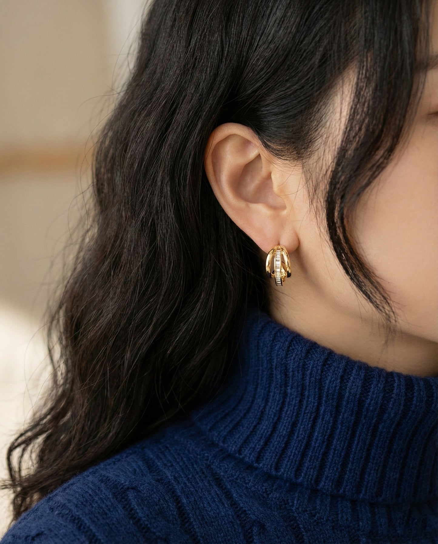 ide view of gold C-curve huggie hoop earrings with baguette CZ stones