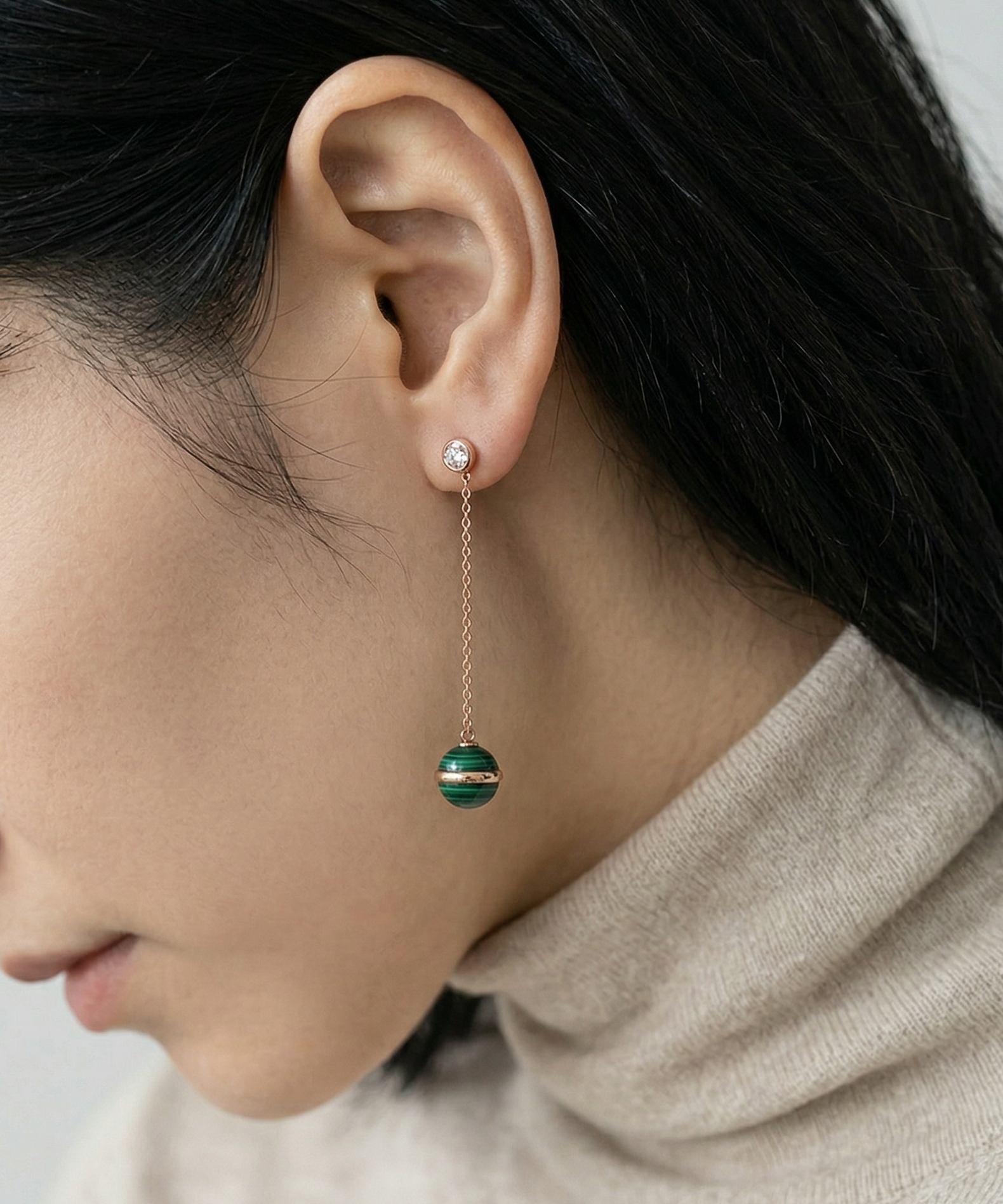 Side profile of model in beige turtleneck wearing 35mm rose gold chain malachite drop earrings, showing full dangle length against jawline