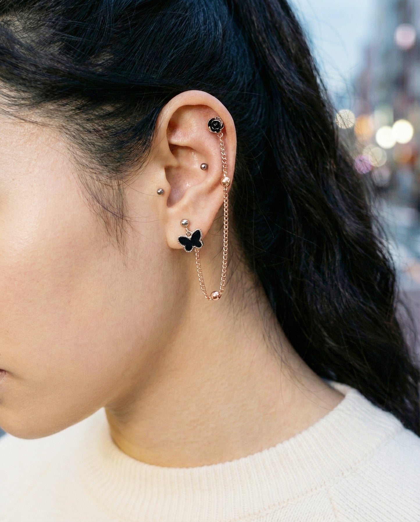Ear model displaying black butterfly rose chain piercing on silicone ear form