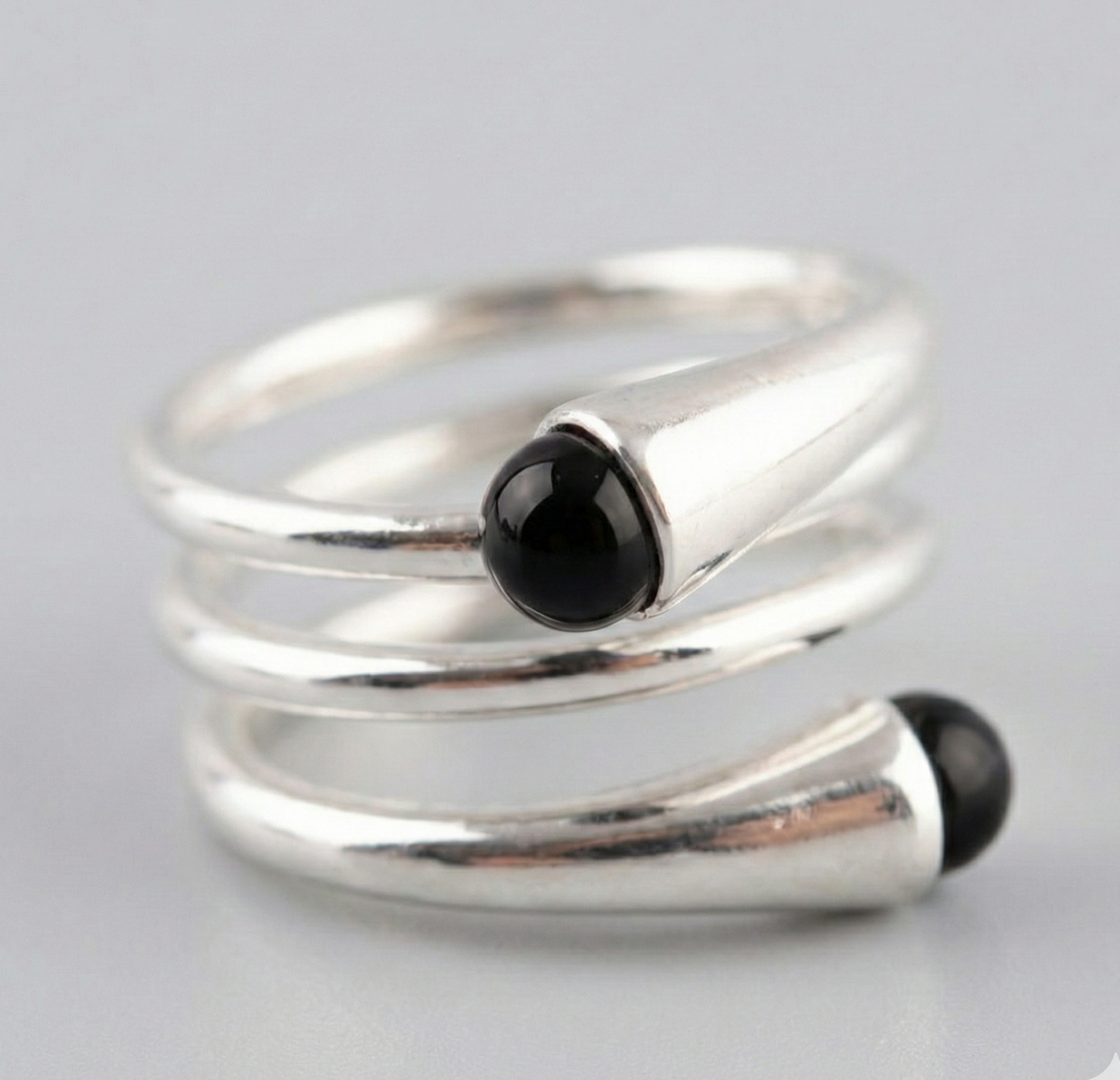  Close-up macro shot of 925 sterling silver spiral wrap ring with dual black onyx beads — chunky coil detail on gray background