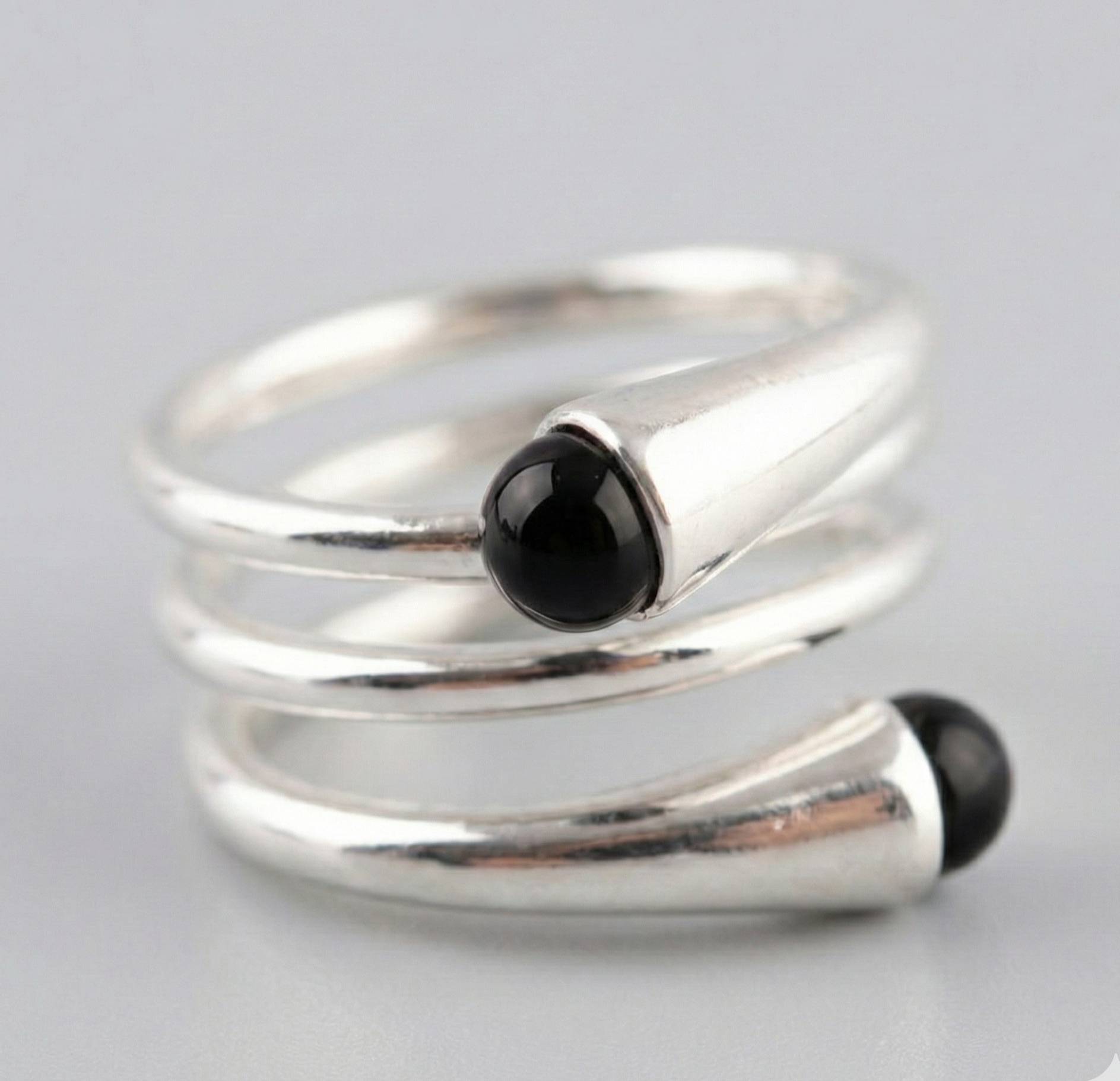  Close-up macro shot of 925 sterling silver spiral wrap ring with dual black onyx beads — chunky coil detail on gray background