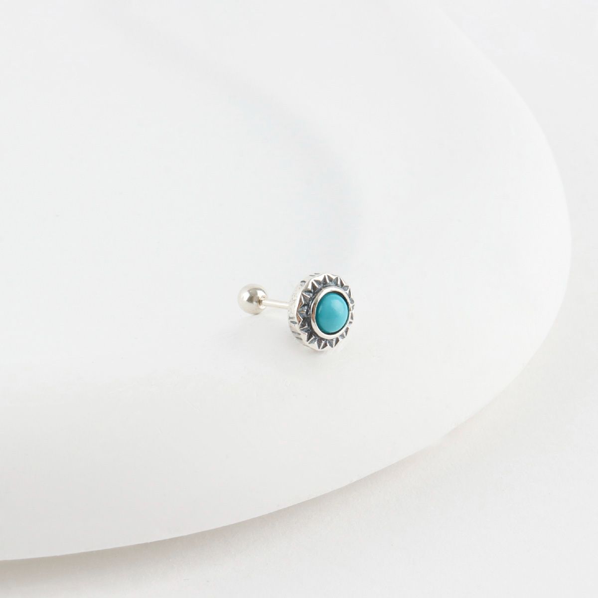 Turquoise sunburst barbell stud earring with vintage silver frame on white surface