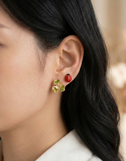 Close-up of a model wearing the Retro Red set, featuring a gold-green clover and a red ladybug stud earring.
