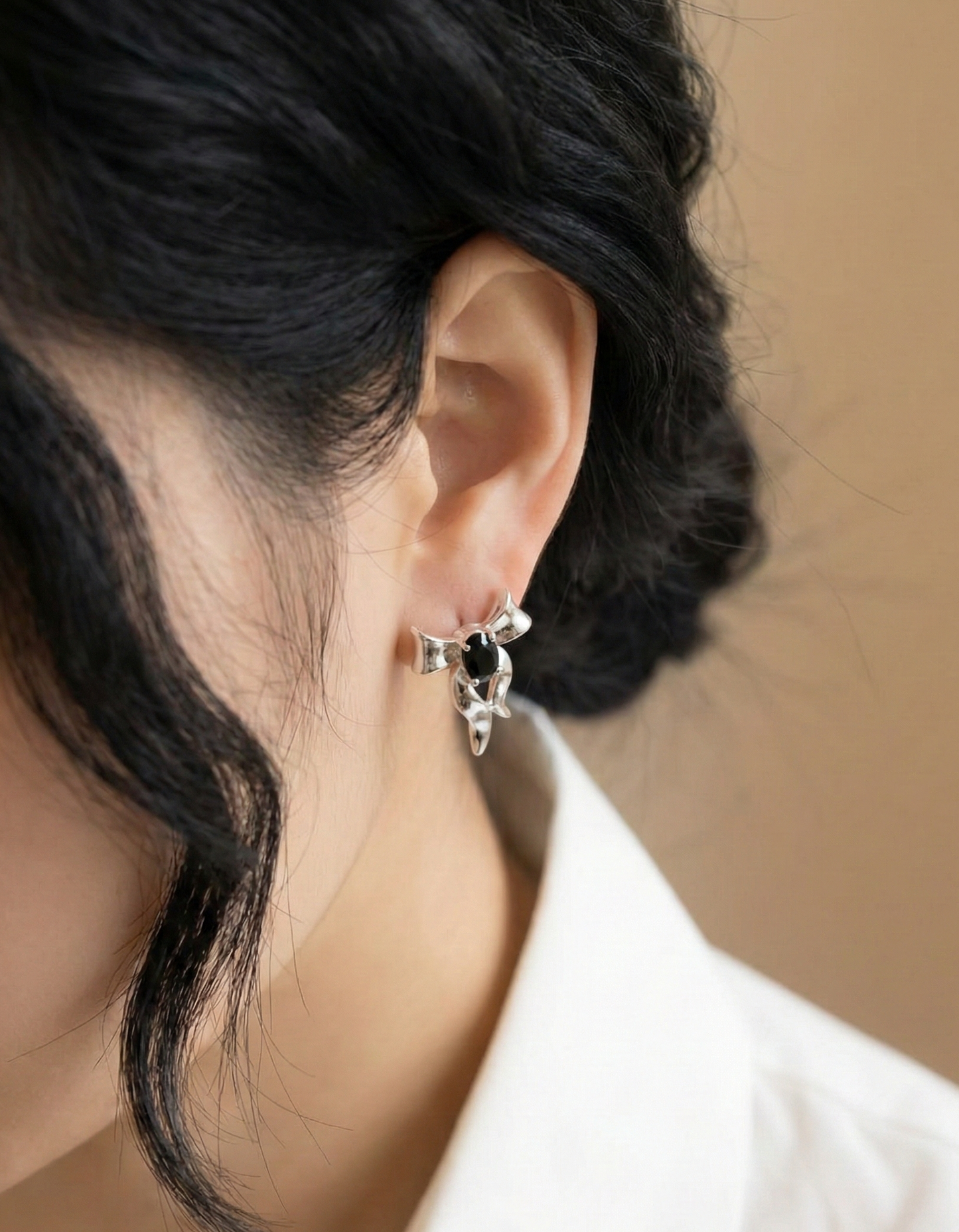 Side profile of woman wearing 925 sterling silver black agate ribbon stud earrings — close-up ear shot