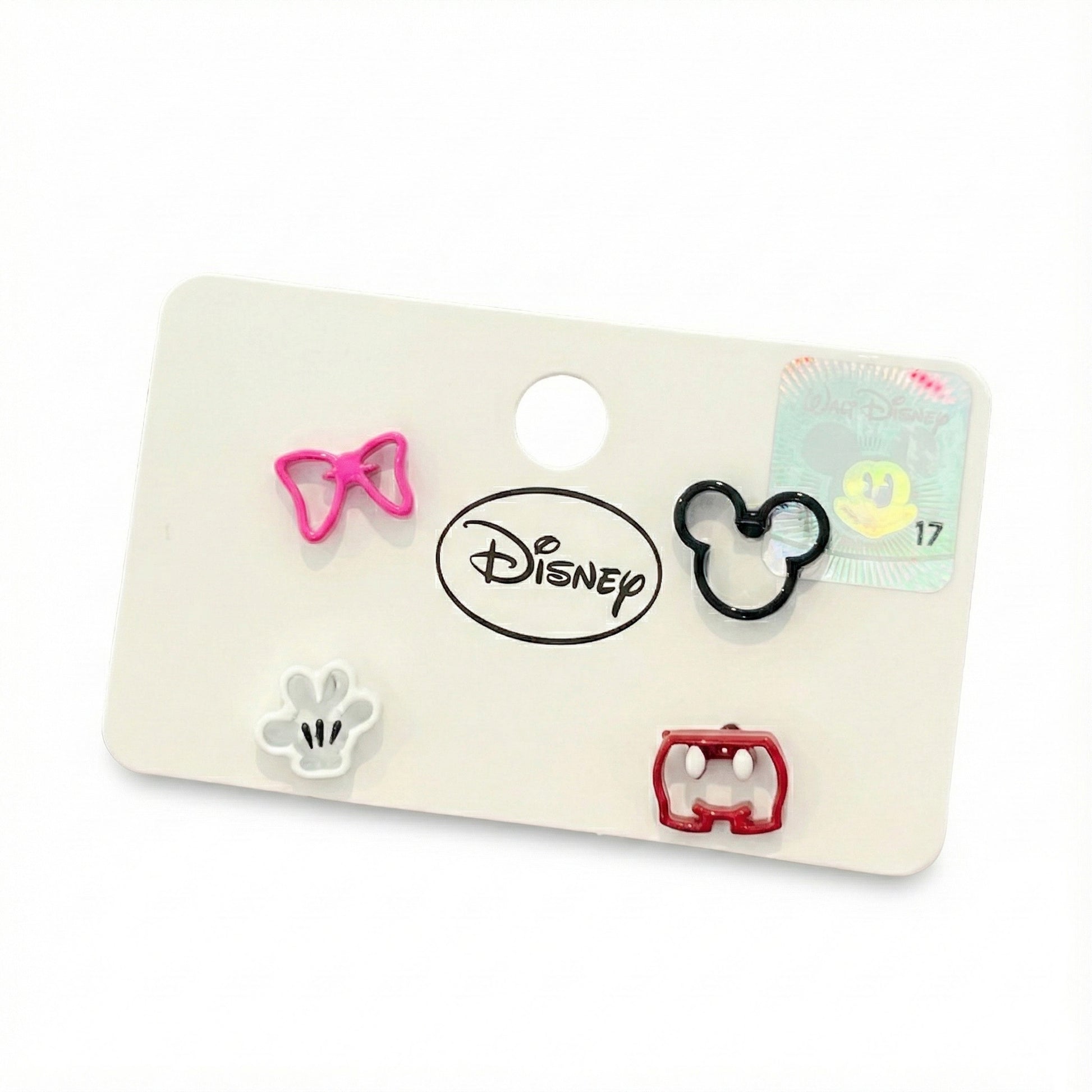 et of four mismatched Disney earrings — pink Minnie bow, white glove, black Mickey silhouette, and red shorts — attached to a branded Disney card with logo and hologram sticker.