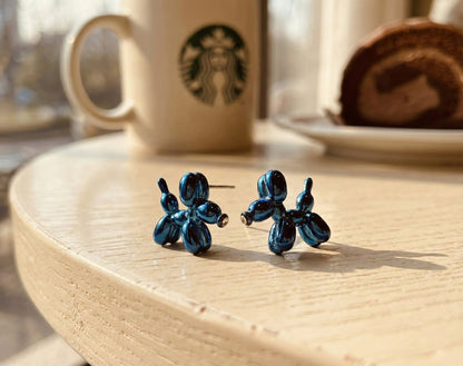 Electric blue balloon dog earrings close-up on wooden surface displaying metallic shine and craftsmanship