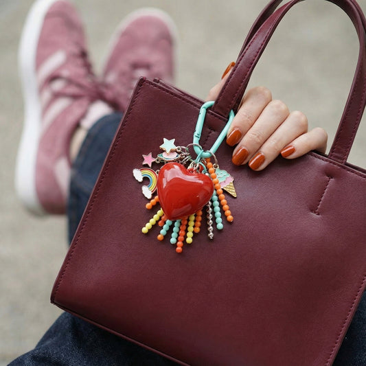 Red heart keychain with rainbow star charms on burgundy mini bag close-up