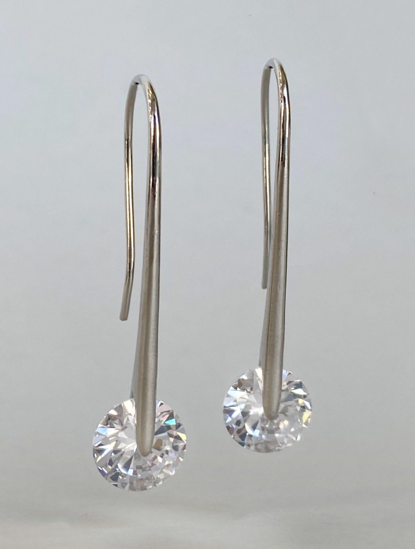  Pair of silver plated 43mm long drop earrings with sparkling 10mm cubic zirconia on white background