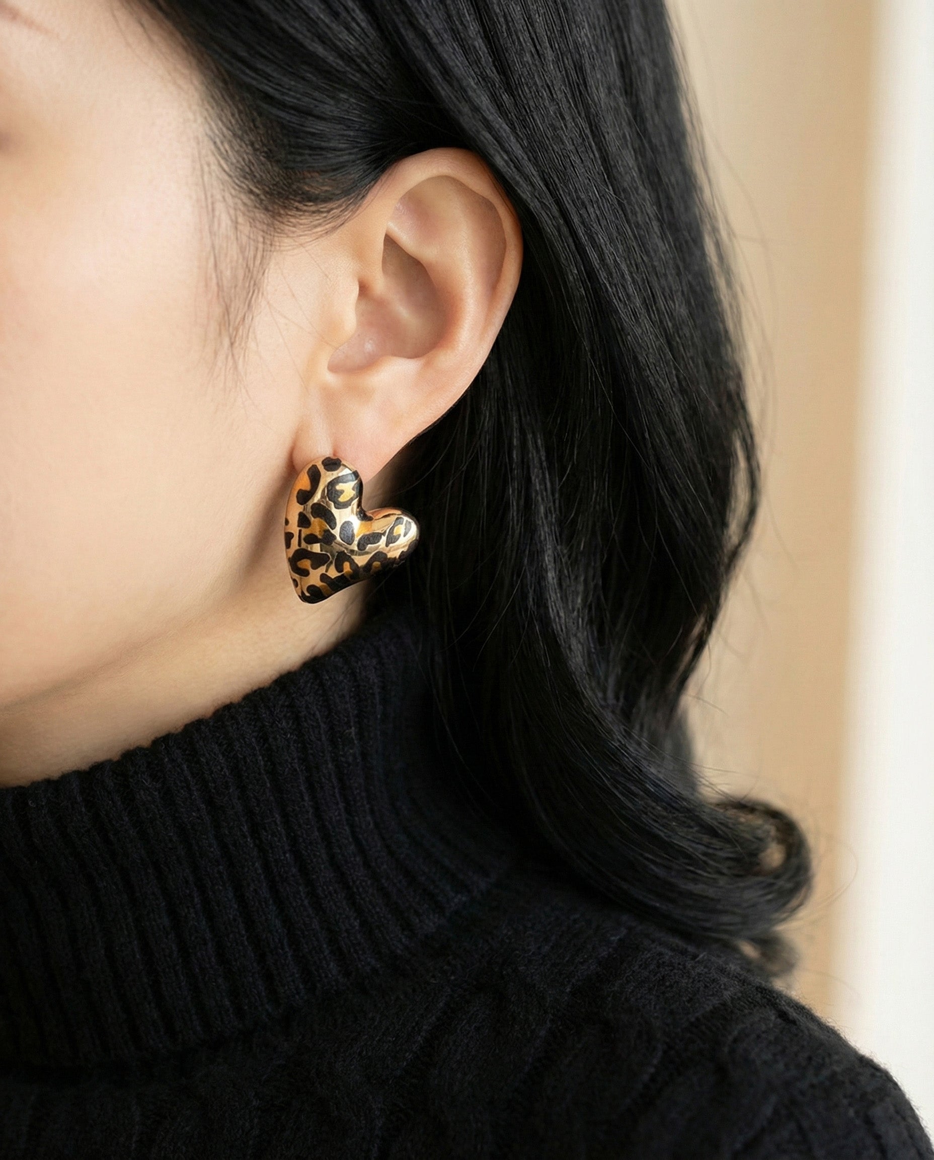 Close-up of leopard heart statement earrings with black turtleneck sweater