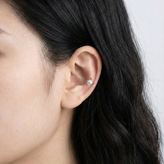 Close-up of Saturn planet pearl orbit barbell piercing on earlobe showing delicate orbit ring and faux pearl