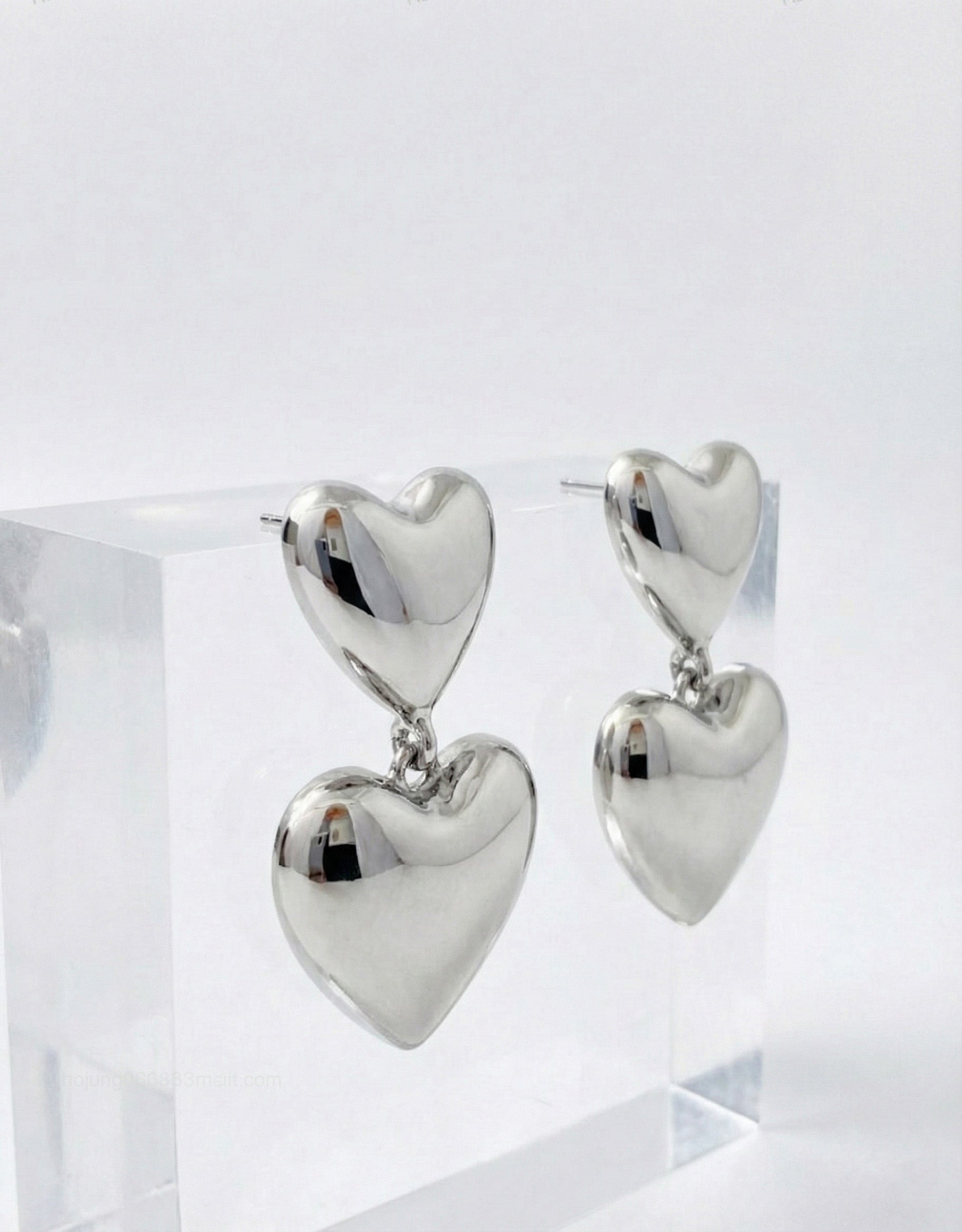 Silver puffed heart drop earrings on acrylic display - hypoallergenic titanium posts