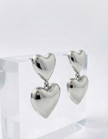 Silver puffed heart drop earrings on acrylic display - hypoallergenic titanium posts