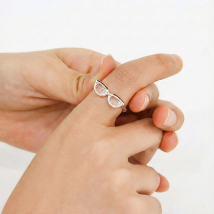 Close-up of hands showing sterling silver eyeglasses ring with detailed black enamel coating and dimensional acrylic lenses