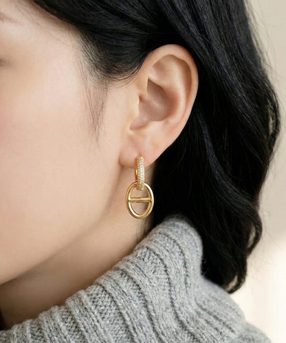 Woman wearing gold anchor link drop earrings with gray knit sweater