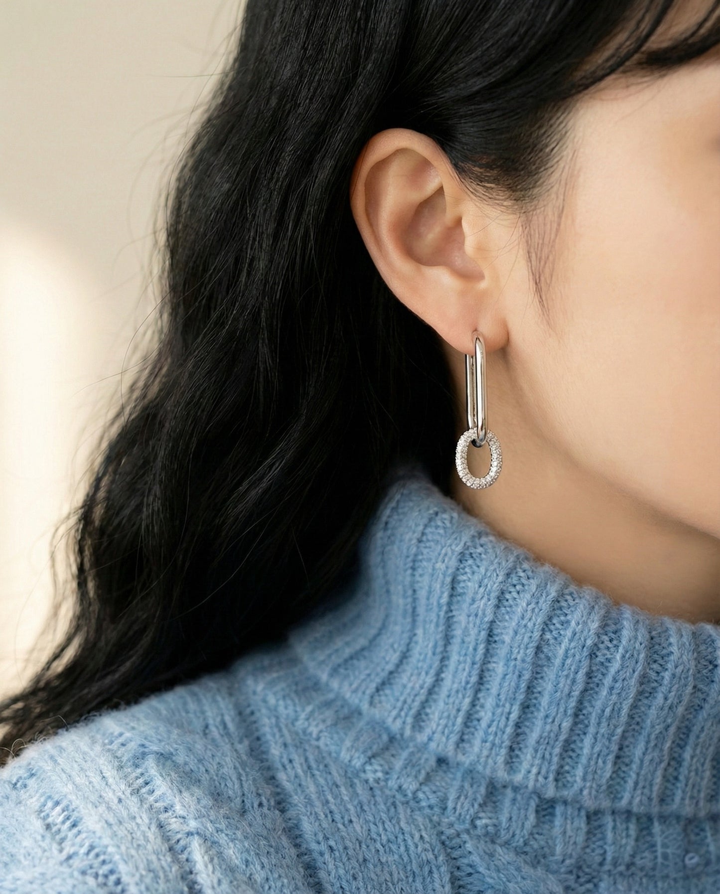 Side view of woman wearing silver oval link drop earrings, bottom pave cubic zirconia