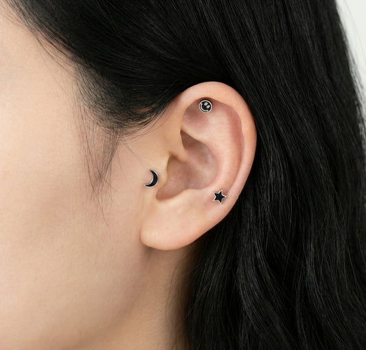 Side profile showing layered ear piercings with surgical steel celestial studs