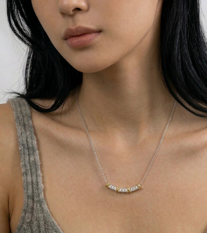 Front view of model wearing two-tone CZ smile bar necklace with grey tank top