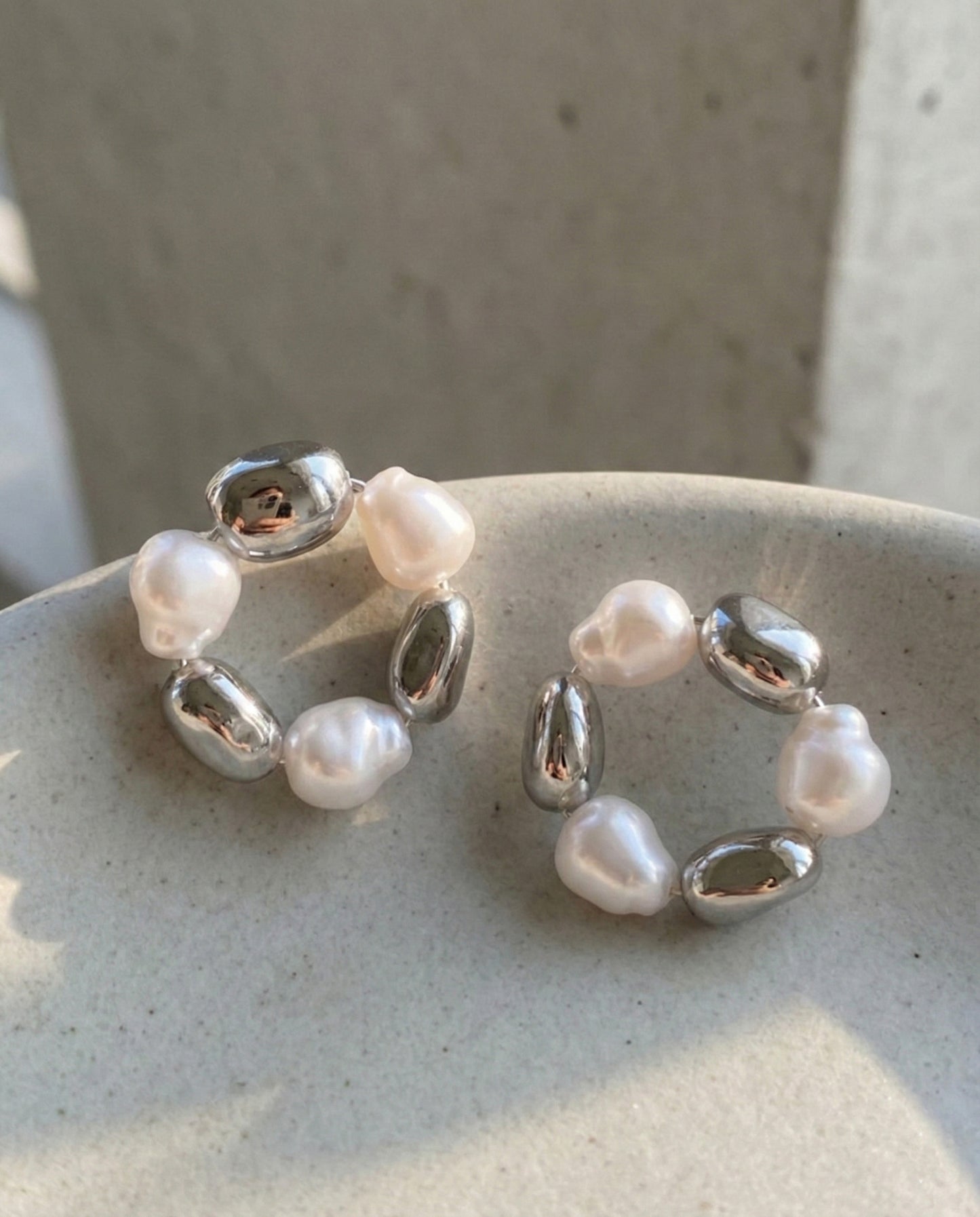 Silver baroque freshwater pearl wreath hoop earrings on ceramic dish showing elegant design details