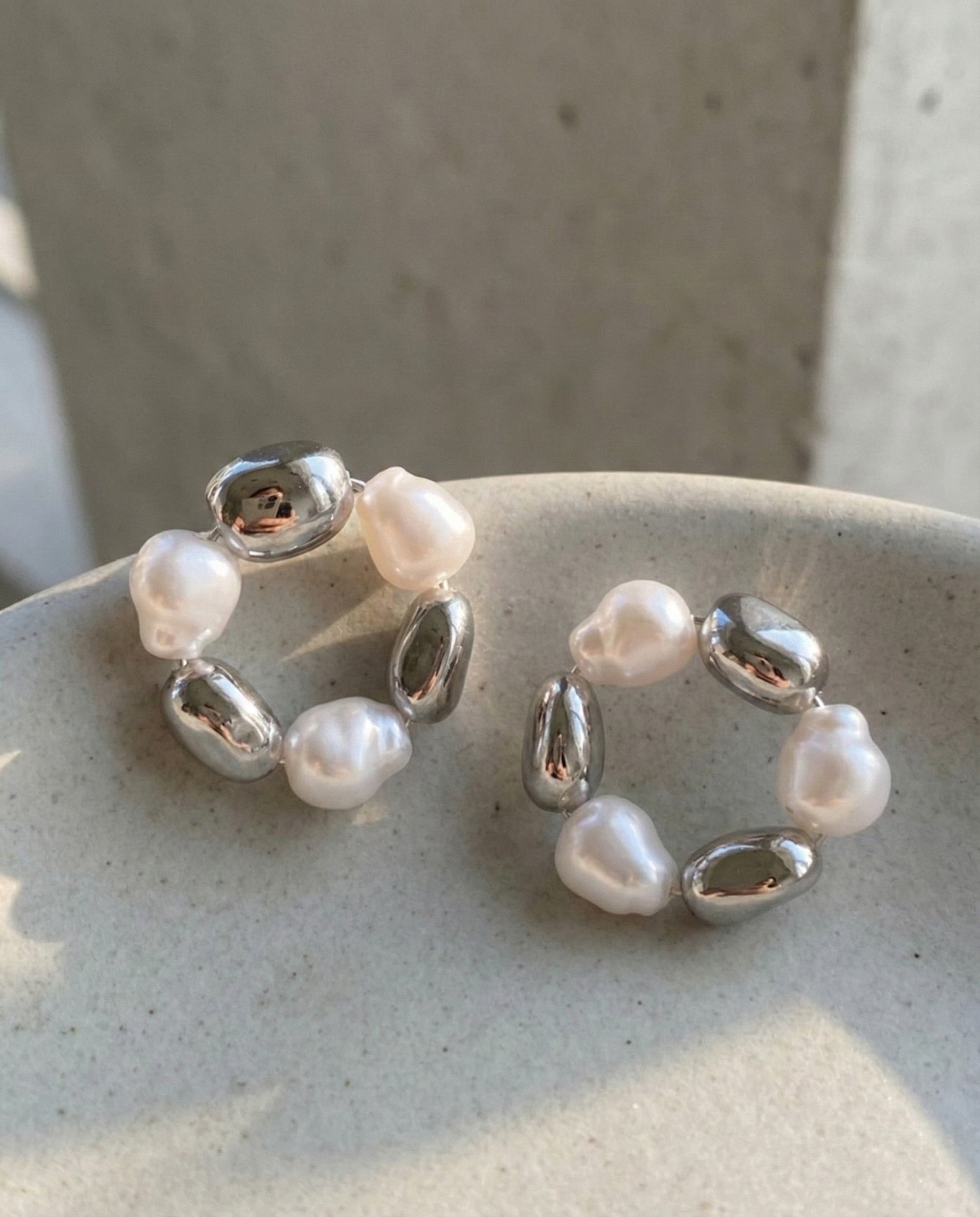 Silver baroque freshwater pearl wreath hoop earrings on ceramic dish showing elegant design details