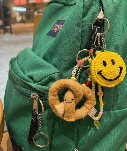 Cute felt pretzel keychain attached to green Jansport backpack with colorful bead charm