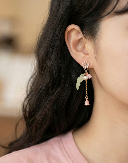 Woman wearing a delicate pink Lily of the Valley dangle earring.