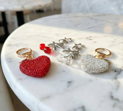 Red and silver heart charm accessories with star pendants on marble surface