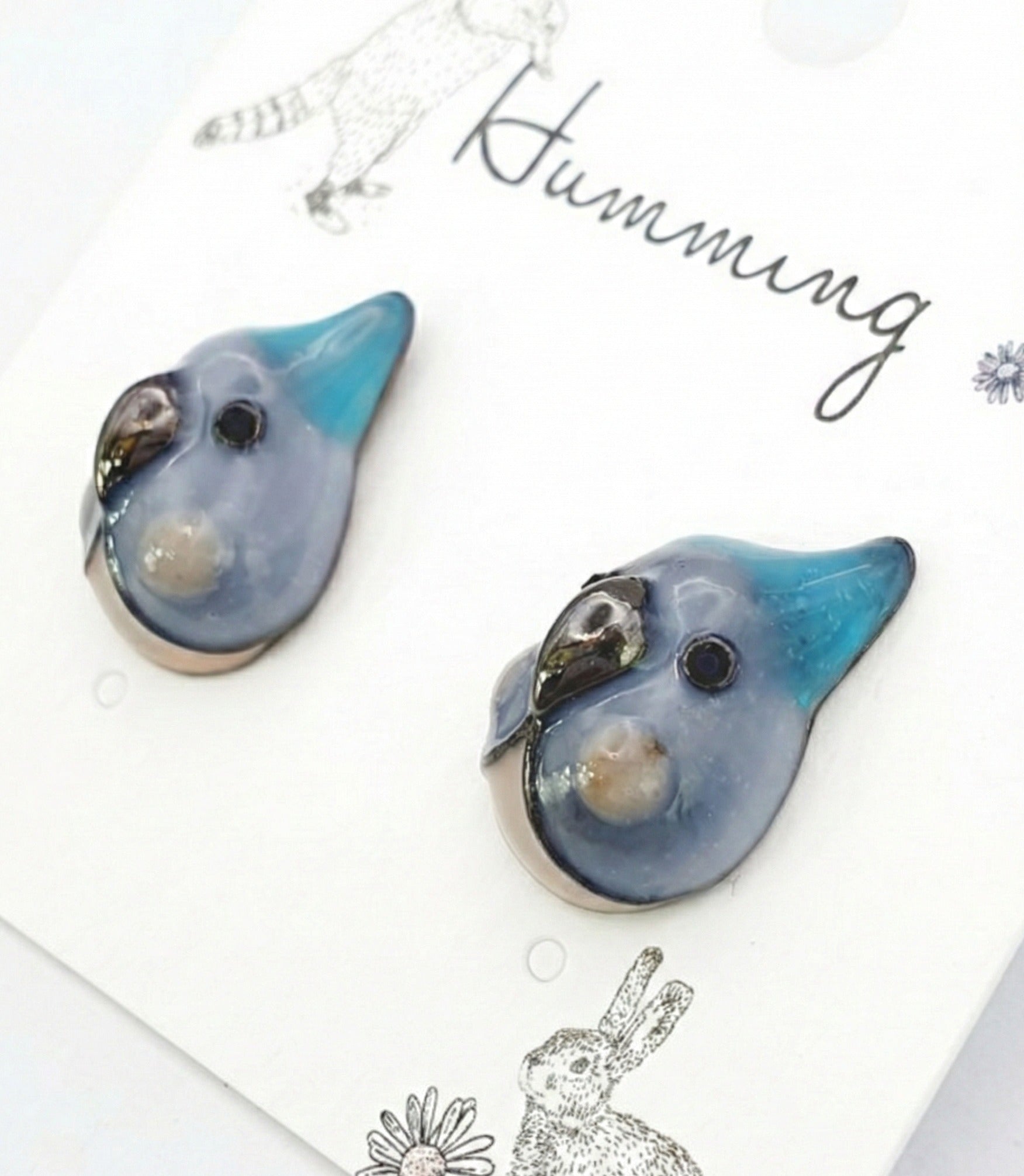  Close-up of blue parrot earring pair with teal beak and slate blue enamel glaze 