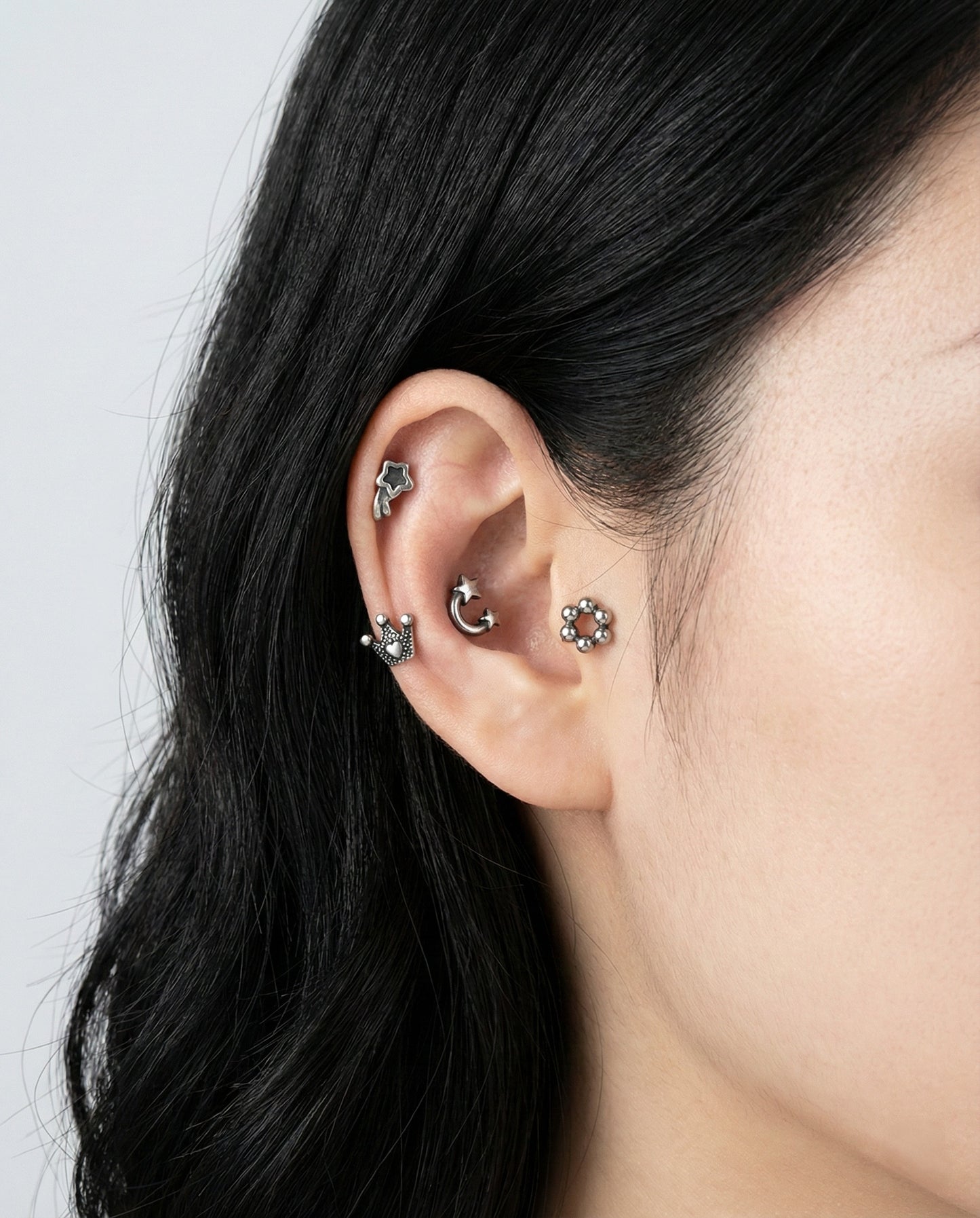 Woman wearing antique surgical steel cartilage piercings in helix tragus conch ear styling